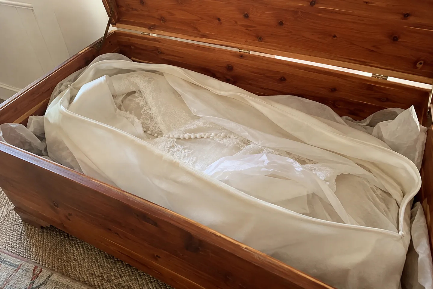 A wedding gown folded in acid-free tissue paper inside an open cedar chest